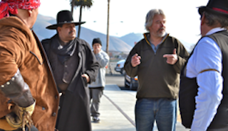 Don directing actors, some of whom are packing heat.